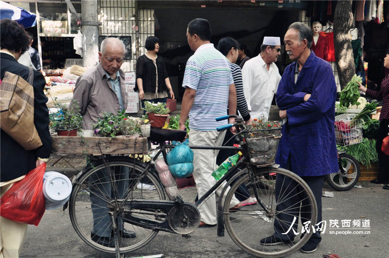 花市的路口,一位推着自行车贩卖自种花的老者,人,花,车成为了一道风景