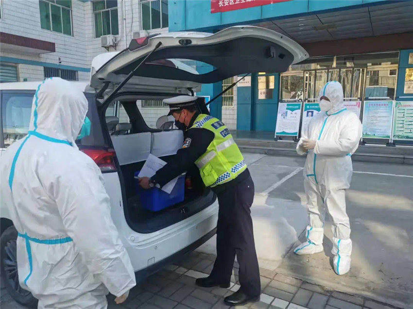 西安公安交警長安大隊在核酸檢測點配合防疫人員工作。