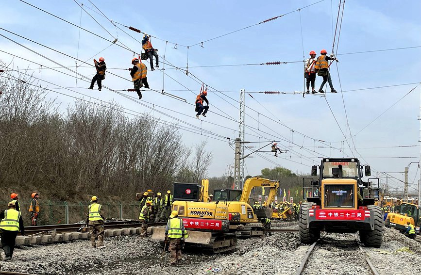 西康铁路便线施工现场，工人们爬上线缆同步移接供电设备。人民网 贾凯璐摄