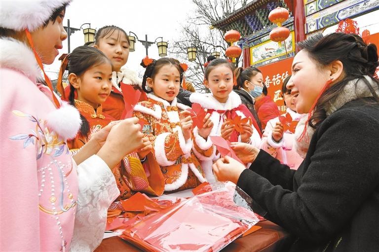 1月20日，西安永兴坊·陕西非遗文化特色街区内，非遗传承人给孩子们教授剪纸、捏面人等非遗技艺。杜玮摄