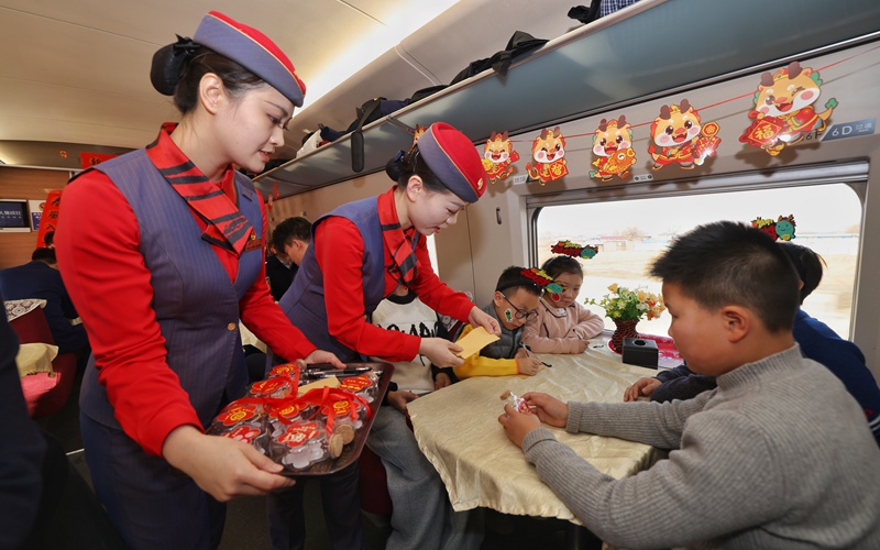 列车工作人员为小旅客们介绍“新春传福漂流瓶”活动。刘松霖 摄