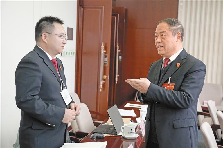 3月8日，全国政协委员巩富文（右）与列席会议的政法部门工作人员进行交流。孙鹏摄