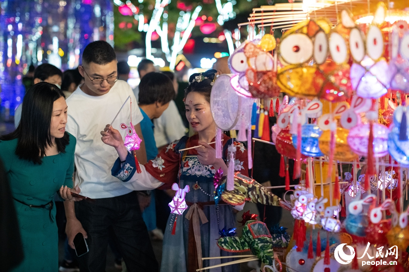 在西安大唐不夜城步行街，游客正在选购手工艺品。人民网记者 翁奇羽摄