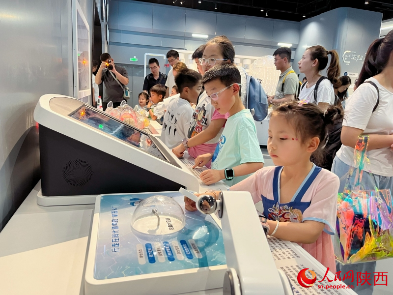 “身边的发明”展区，孩子们与展品积极互动，探索科学的奥秘。人民网记者 魏鑫摄