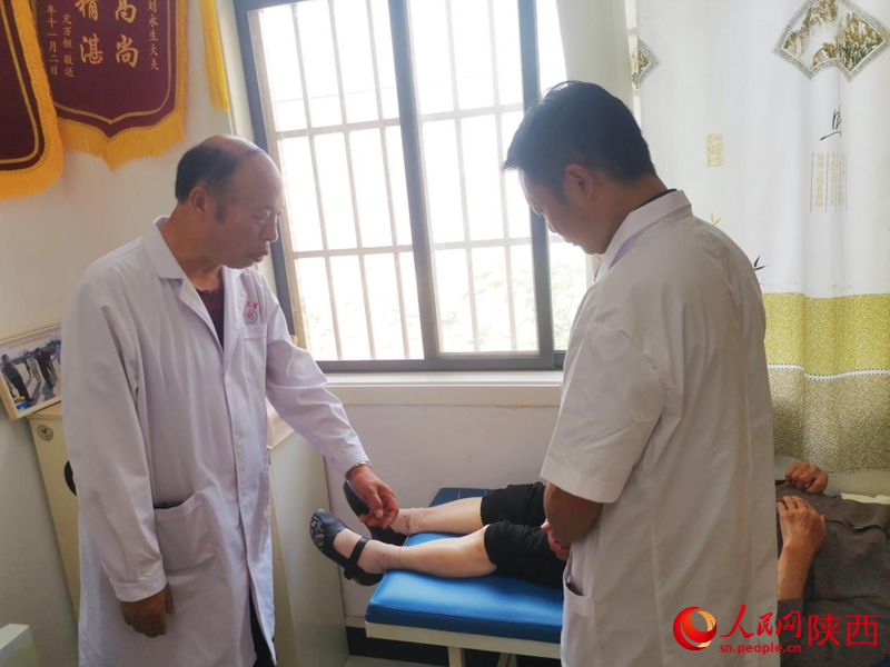 刘永生正在指导儿子刘博诊断患者病情。人民网 王丽摄