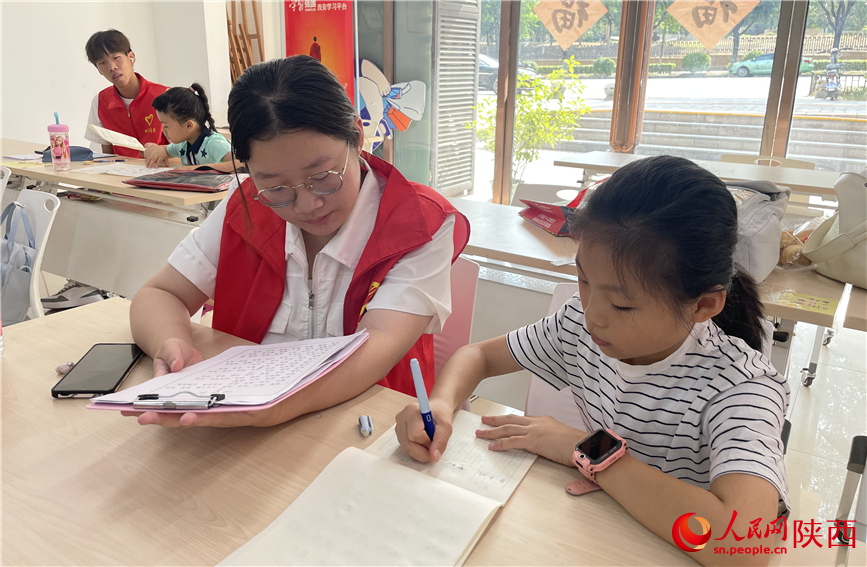 7月16日，西安市新城区明宫社区的志愿者在给孩子辅导作业。人民网记者 李志强摄