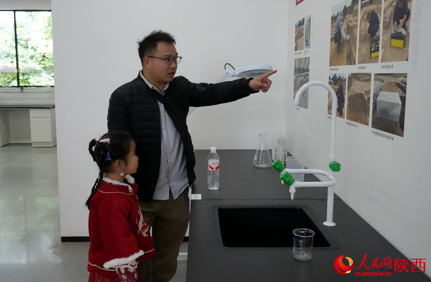 一名观众一边指着墙上展陈的照片一边向女儿讲述文物保护的过程。