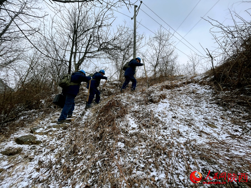 國家電網寶雞供電公司輸電運檢中心秦嶺輸電運維班成員踩著積雪巡線護網。人民網記者 魏鑫攝