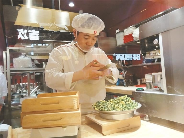 4月8日，在西安市老城根街区的“莲湖区明厨亮灶智慧监管示范街”，一家餐饮店的厨师在后厨包饺子。透过玻璃墙，顾客及行人可以看到后厨状况。