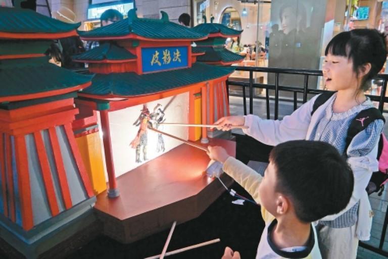 西安各大商圈假期推出丰富活动。图为孩子们在老城根G-PARK体验皮影戏。谢伟摄