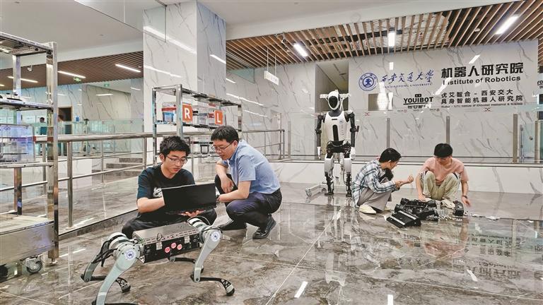 六月三十日,西安交通大学具身智能机器人研究院副院长徐俊(左二)在实验室指导学生调试机器人设备(资料照片)。 记者 陈绮珠摄