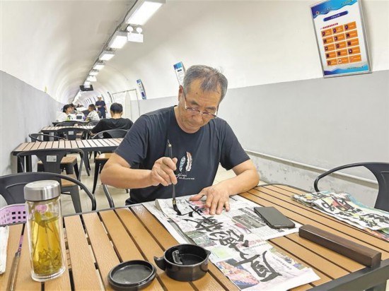8月7日，一位老人在西安人防纳凉中心乘凉、写字。记者 周明摄