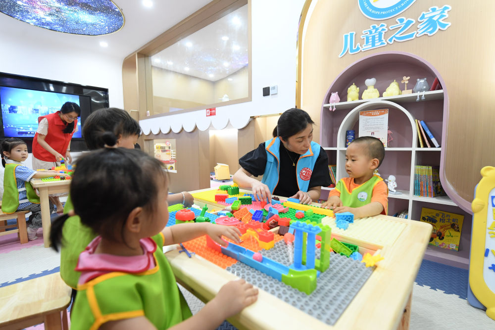 2023年5月29日，在浙江省湖州市爱山街道利民社区，一个公益组织的老师带着儿童玩积木。新华社记者 翁忻旸 摄